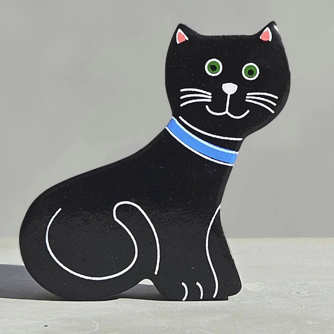 A magnetic wooden cat play figure with a blue collar.