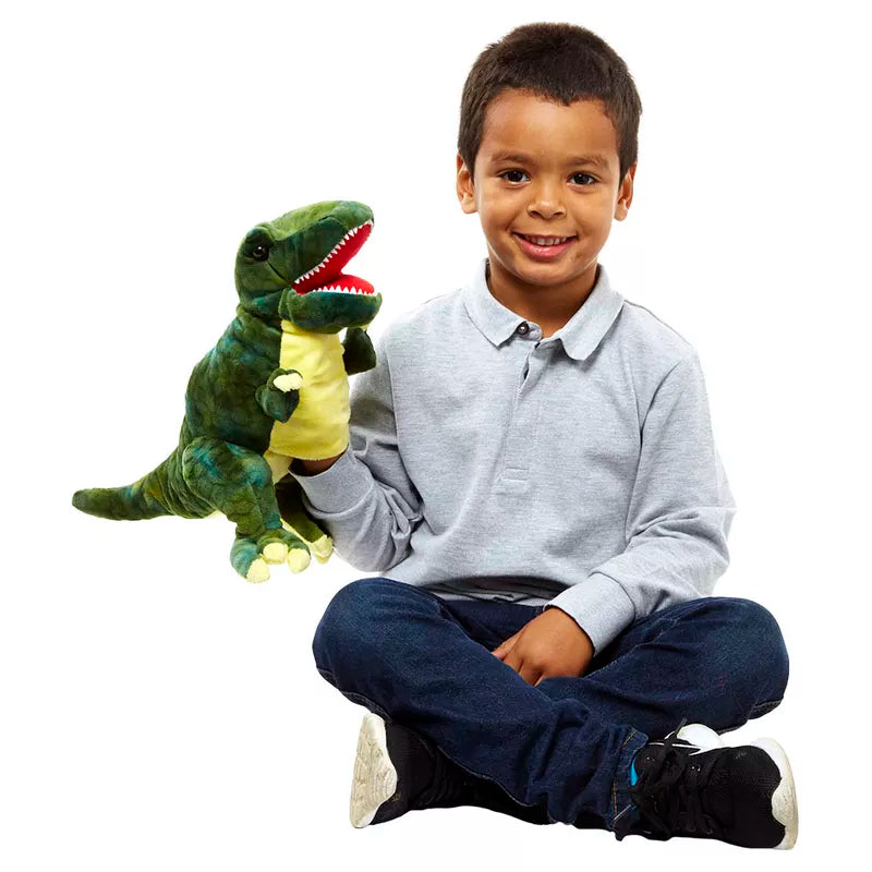 A young boy is sitting on the floor with The Puppet Company Baby T-Rex Green.