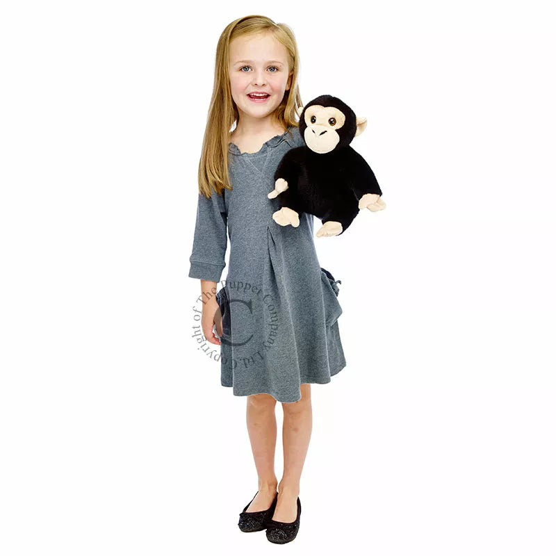 A little girl holding the Puppet Company Full-bodied Hand Puppet Chimp.
