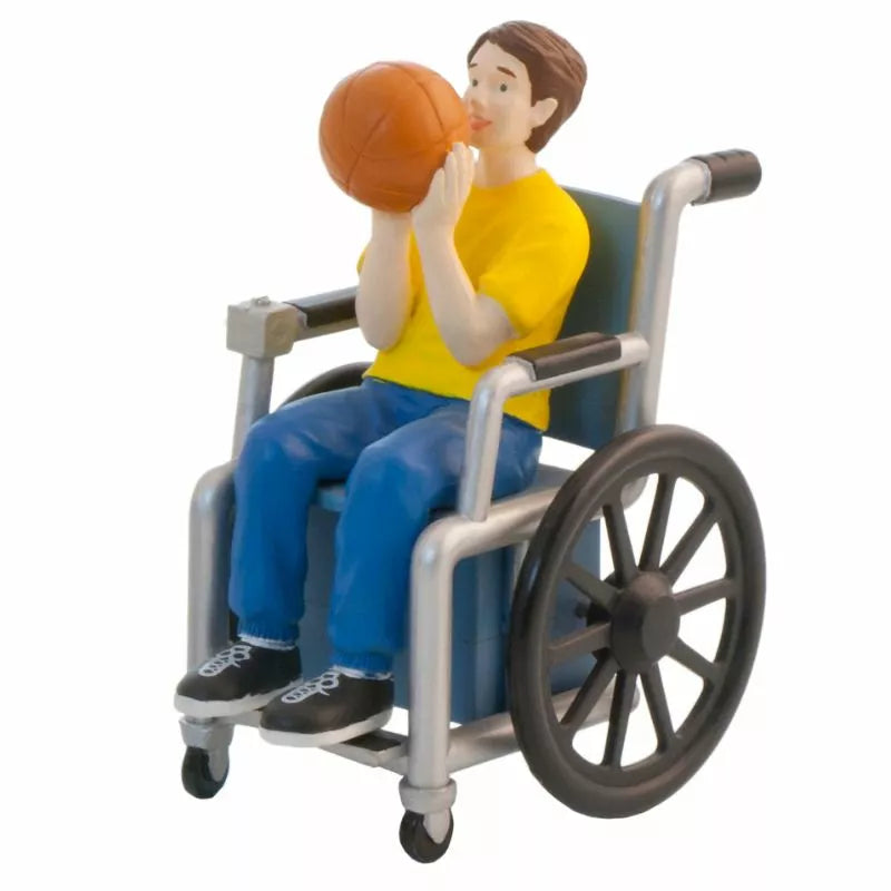 A wheelchair-bound man with functional diversity holds a basketball during a kids' puppet show.